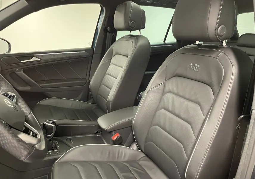 Intérieur du Volkswagen Tiguan 2024 vu côté gauche, sièges en cuir noir avec logo R et finitions soignées.