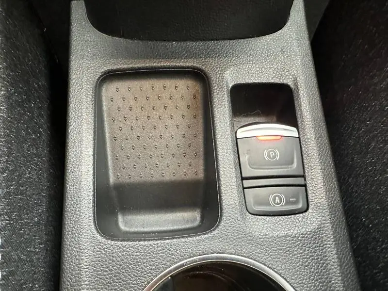 Gros plan sur la console centrale noire du Renault Captur 2025, avec bouton de frein à main électronique allumé.