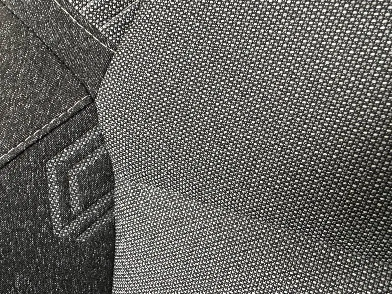 Détail du tissu gris et noir avec surpiqûres blanches sur le siège avant du Renault Captur 2025 hybride.