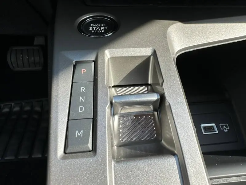 Gros plan sur la console centrale de la Peugeot 308 2025, montrant la commande de boîte auto et le bouton start/stop.