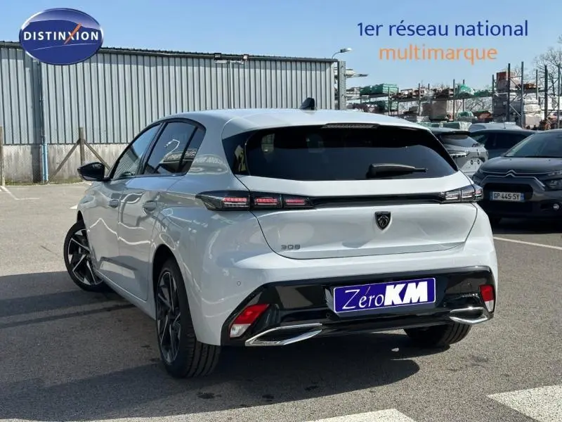 Vue 3/4 arrière droite d'une Peugeot 308 blanche avec feux arrière LED et jantes alliage noires.