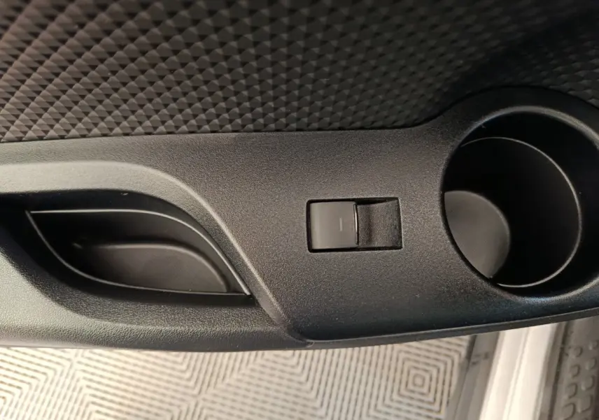 Gros plan sur la poignée de porte intérieure noire et le bouton de verrouillage d’un Toyota C-HR gris clair.