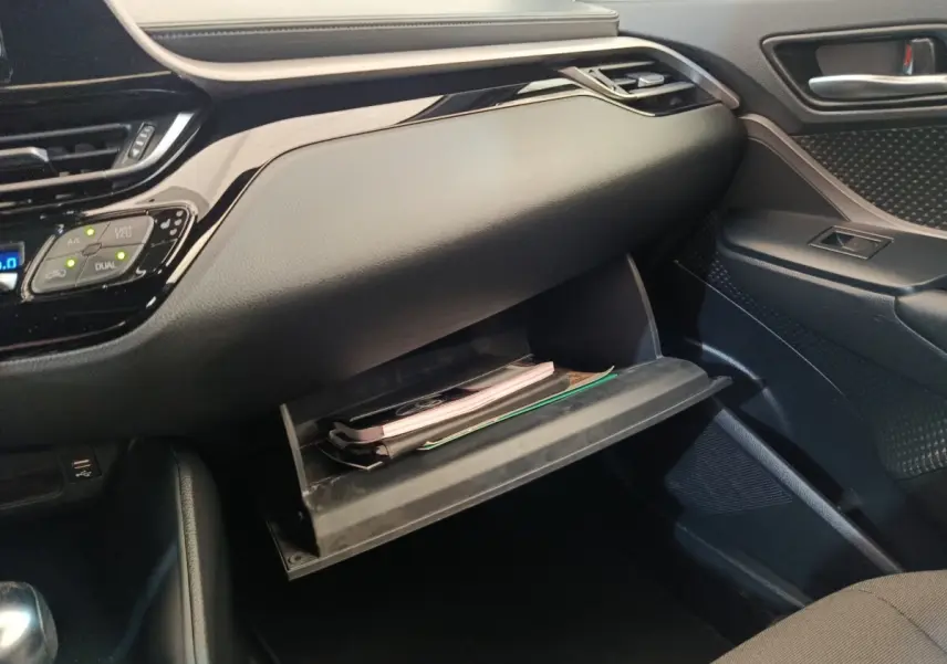 Intérieur du Toyota C-HR 2.0 Hybride 2022, vue côté passager sur la boîte à gants ouverte avec documents visibles.