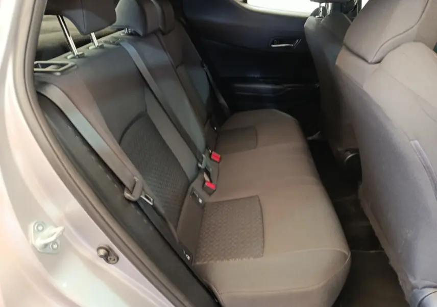 Vue intérieure côté gauche sur la banquette arrière grise du Toyota C-HR 2.0 Hybride 2022 avec ceintures et appuie-têtes visibles.