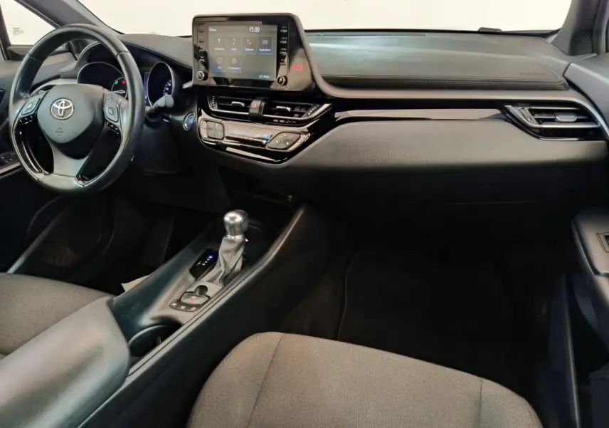 Intérieur avant du Toyota C-HR gris clair 2022, tableau de bord avec écran tactile central et volant multifonctions cuir.