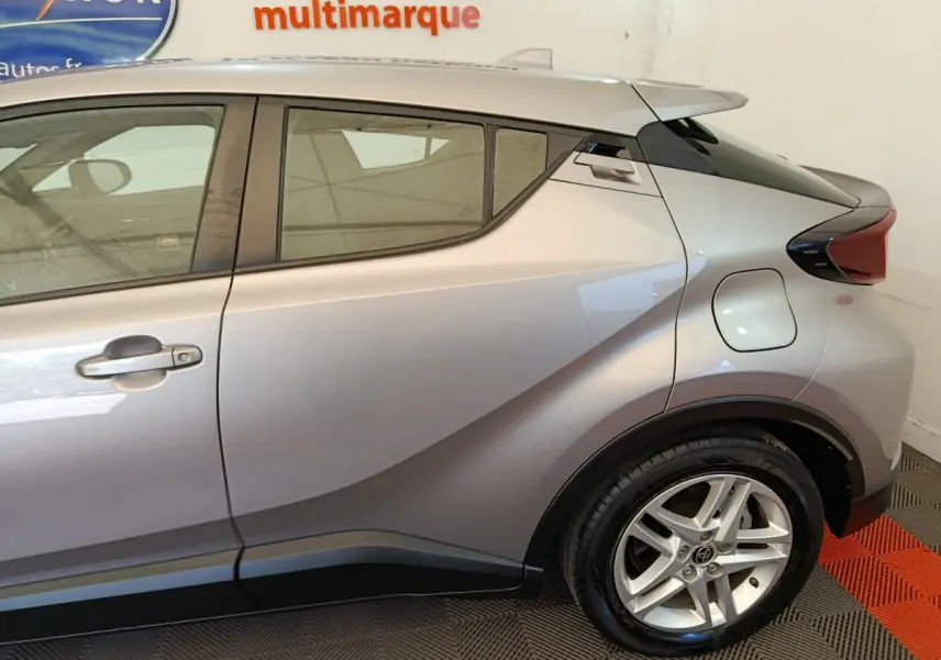Vue latérale droite du Toyota C-HR gris clair 2.0 Hybride 184 avec jante alliage et lignes anguleuses marquées.