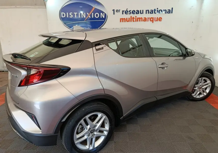 Vue 3/4 arrière droite du Toyota C-HR gris clair hybride 2022 avec toit noir et jantes alliage.