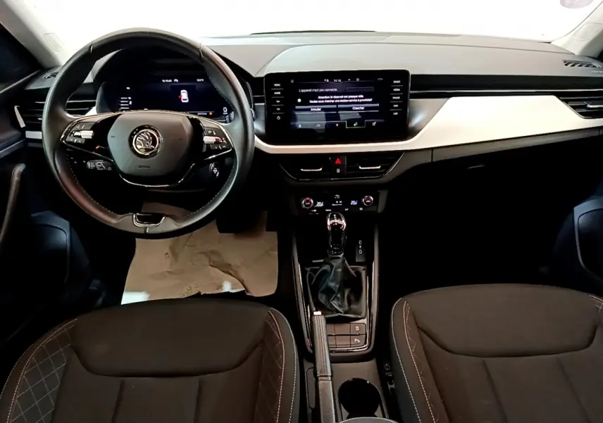 Intérieur noir du Skoda Kamiq 2022 vu de face, tableau de bord moderne avec écran tactile et volant multifonctions.