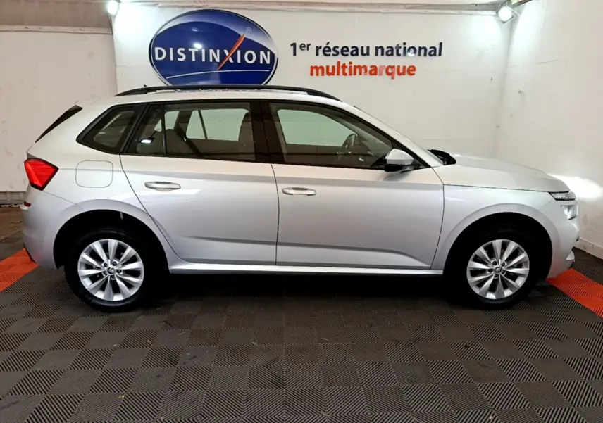 Profil latéral droit d'un Skoda Kamiq gris clair 2022 garé en intérieur avec rails de toit noirs visibles.