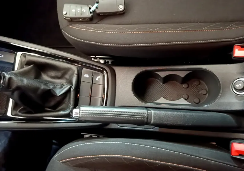 Vue plongeante sur la console centrale noire du Skoda Kamiq 2022, avec levier de frein à main et porte-gobelets.