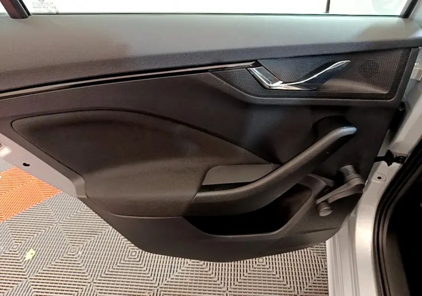 Vue rapprochée de la porte avant droite noire d'un Skoda Kamiq gris clair avec poignée chromée et manivelle de vitre.