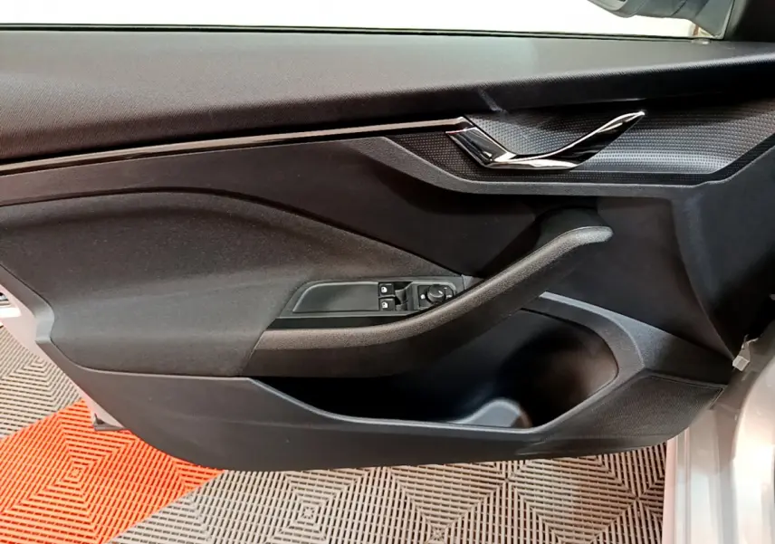 Panneau de porte côté gauche gris foncé du Skoda Kamiq 2022, avec poignée intégrée et commandes électriques.