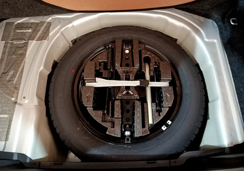 Roue de secours galette noire avec outils de bord, logée dans le coffre gris clair du Skoda Kamiq 2022.