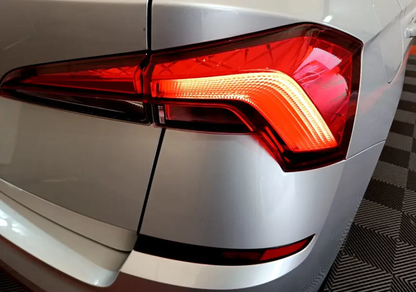 Gros plan sur le feu arrière droit rouge d’un Skoda Kamiq gris clair 2022, avec carrosserie lisse et reflets.