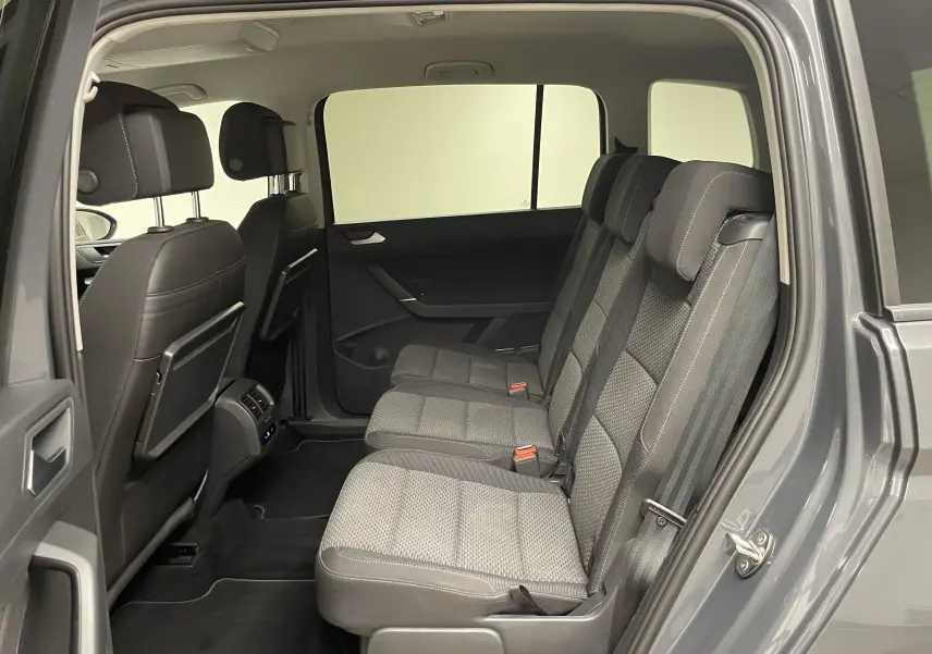 Intérieur arrière du Volkswagen Touran gris Dauphin, vue côté droit sur les trois sièges passagers en tissu gris.