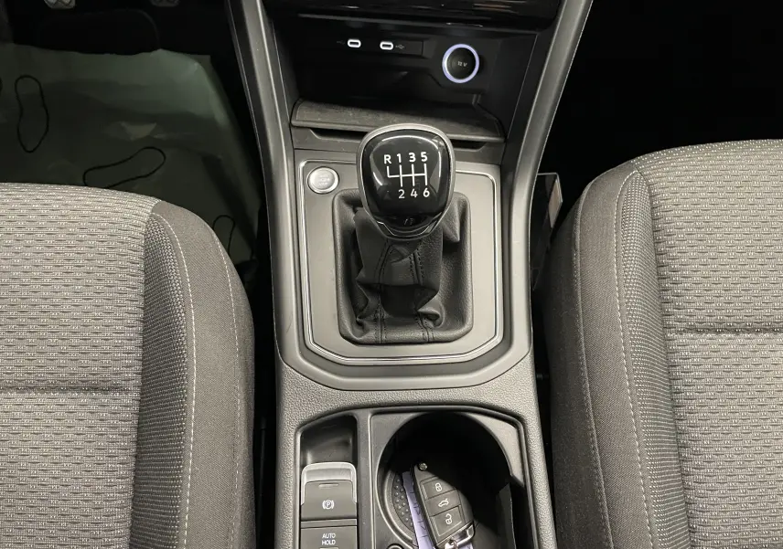 Vue intérieure centrée sur la console centrale du Volkswagen Touran 2024, levier de vitesse manuel et clé Keyless Access.