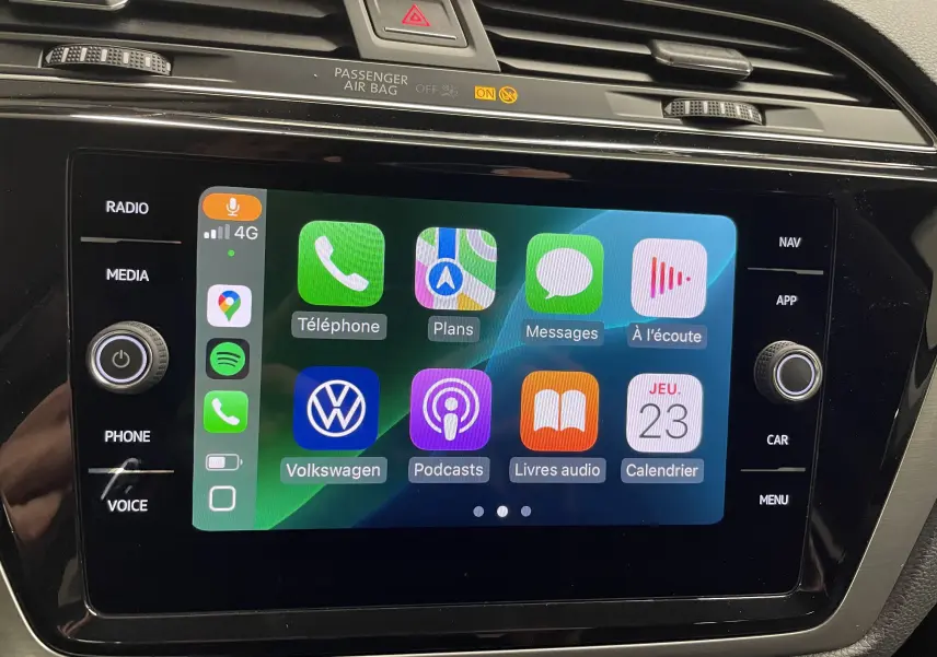 Écran tactile central du Volkswagen Touran 2024 affichant Apple CarPlay avec icônes colorées, entouré de commandes noires.