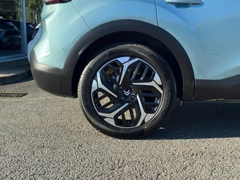 Gros plan sur la roue arrière droite d'une Citroën C4 gris clair 2024 avec jante alliage au design géométrique.