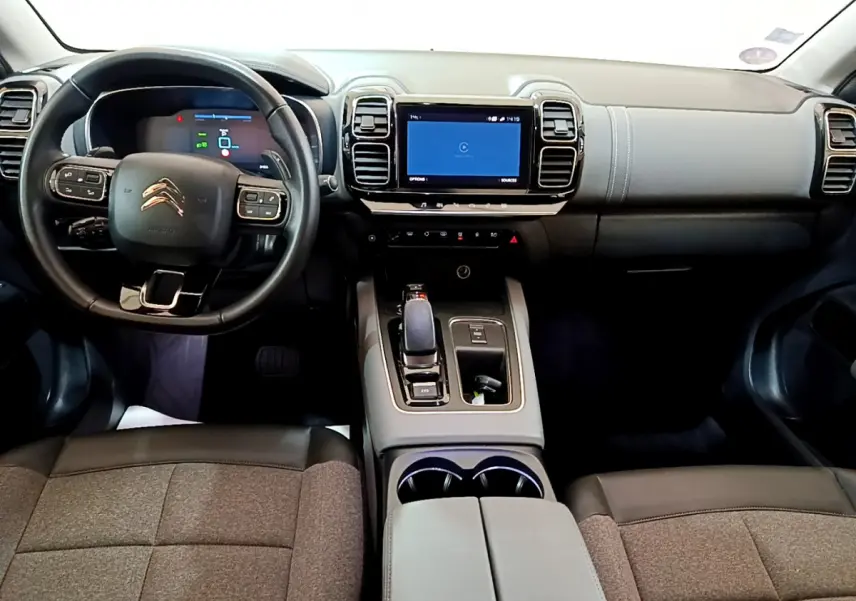 Vue intérieure avant du Citroën C5 Aircross Hybrid gris clair, avec tableau de bord numérique et écran tactile central.