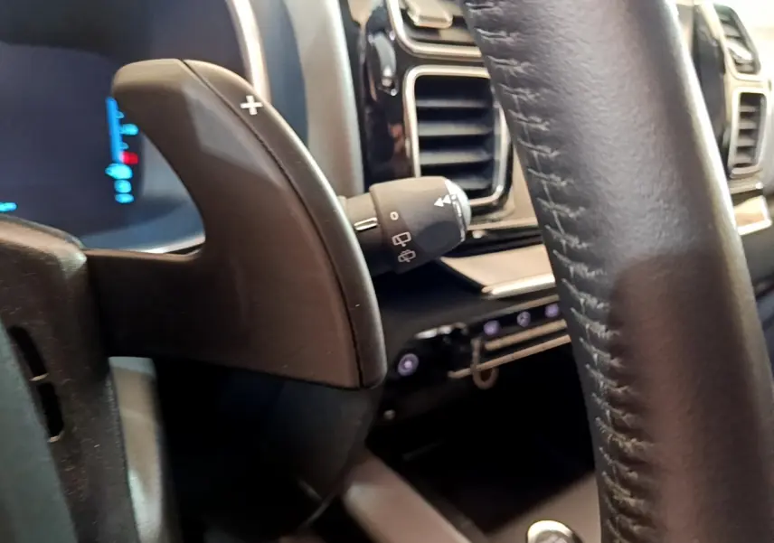 Gros plan sur la palette de changement de vitesse et le volant cuir noir du tableau de bord du Citroën C5 Aircross Hybrid 225 ë-EAT8 Business.