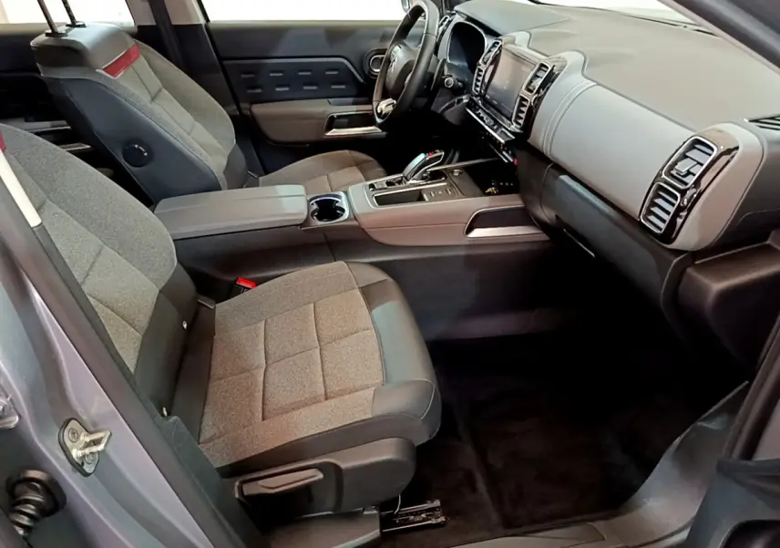 Vue intérieure côté conducteur de la Citroën C5 Aircross Hybrid gris clair, avec tableau de bord moderne et sièges tissu gris.