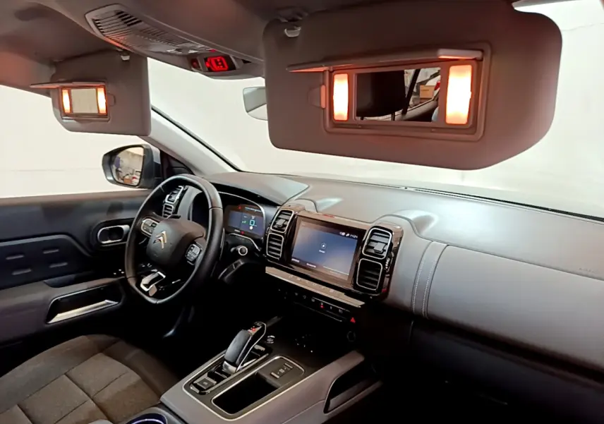 Intérieur du Citroën C5 Aircross Hybrid gris clair vu côté conducteur, tableau de bord et écran tactile éclairés.