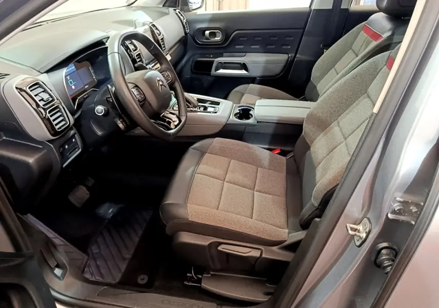 Intérieur côté conducteur du Citroën C5 Aircross Hybrid gris clair, sièges tissu et cuir, tableau de bord moderne avec écran numérique.