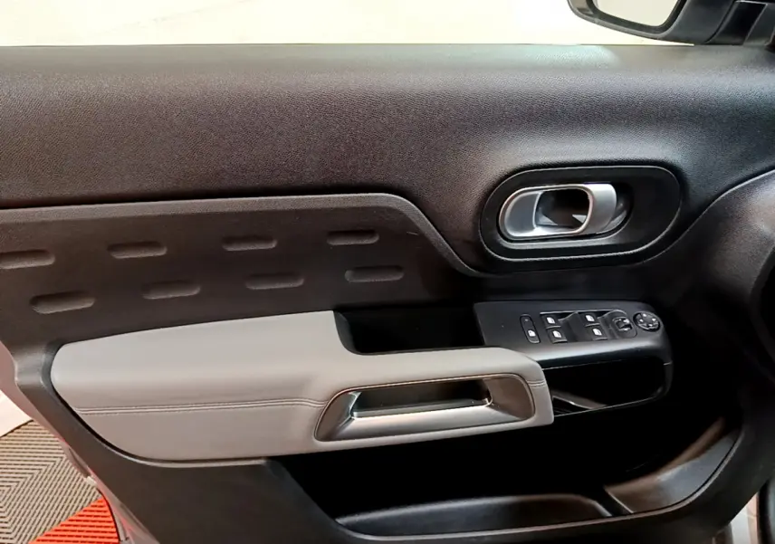 Gros plan sur la porte côté gauche du Citroën C5 Aircross Hybrid gris clair avec commandes de vitres et poignée intégrée.