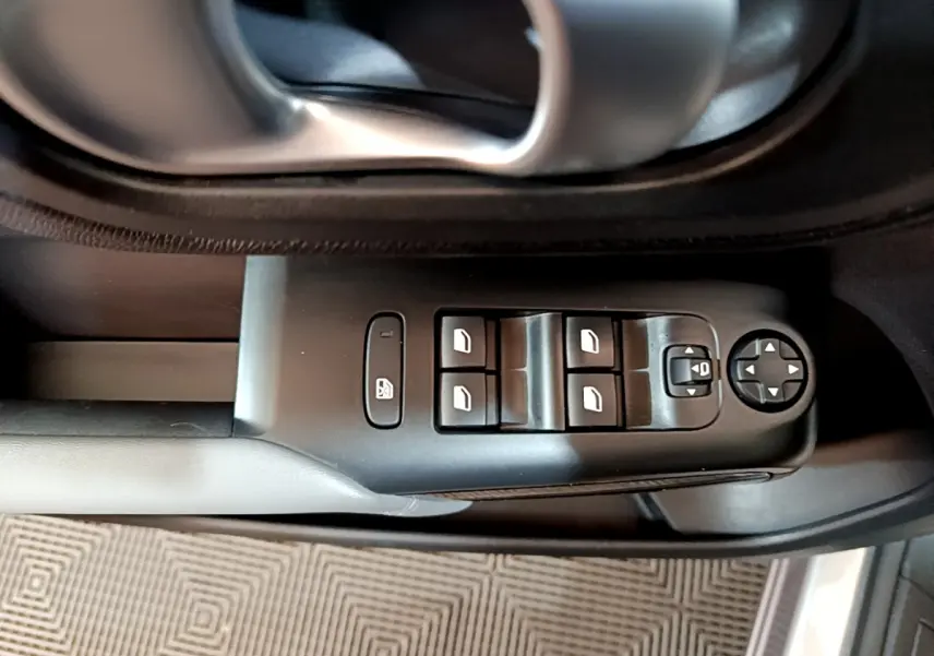 Gros plan sur la commande des vitres et rétroviseurs côté conducteur d'une Citroën C5 Aircross Hybrid gris clair.