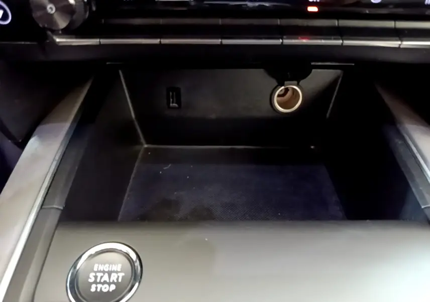 Gros plan sur la console centrale noire du Citroën C5 Aircross Hybrid avec bouton démarrage et prise 12V visible