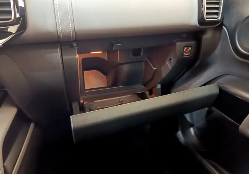 Intérieur du Citroën C5 Aircross Hybrid 225, vue rapprochée de la boîte à gants ouverte avec éclairage intérieur.