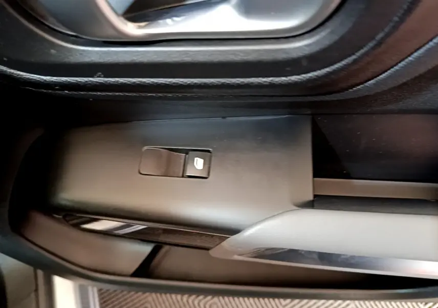 Gros plan sur le bouton de commande de vitre électrique côté gauche dans l'habitacle du Citroën C5 Aircross Hybrid 225 gris clair.