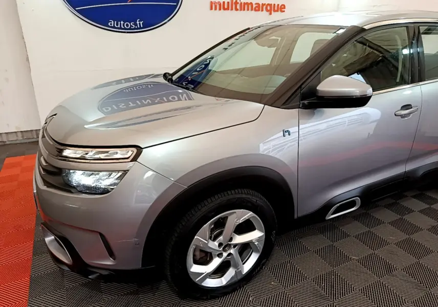 Vue 3/4 avant droit d'un Citroën C5 Aircross Hybrid gris clair avec phares LED et jantes alliage.