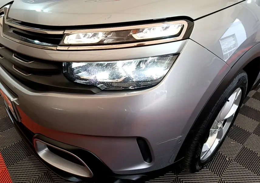Gros plan sur l'avant droit gris clair du Citroën C5 Aircross Hybrid 225 avec phares LED allumés et jante visible.