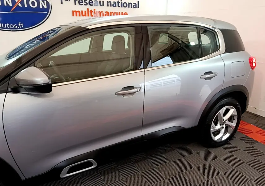Profil côté gauche d'un Citroën C5 Aircross Hybrid gris clair, mettant en valeur ses lignes fluides et ses jantes modernes.