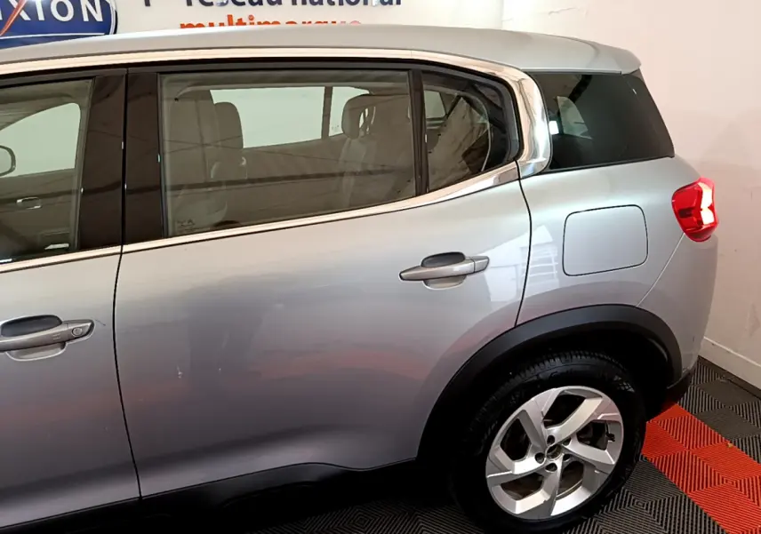 Vue latérale droite sur l'arrière d'un Citroën C5 Aircross Hybrid gris clair avec jante alliage et vitres teintées.