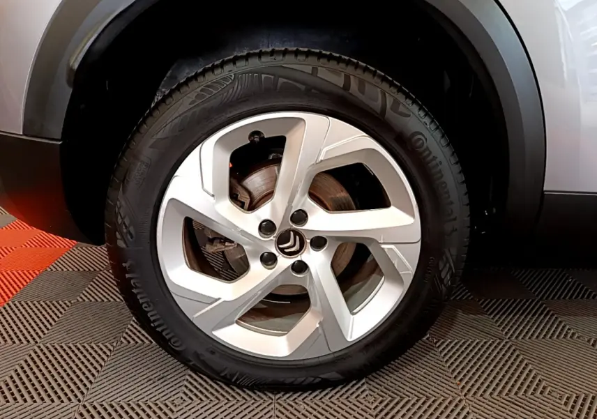 Gros plan sur la roue avant droite gris clair d'un Citroën C5 Aircross Hybrid 225 ë-EAT8 Business avec jante alliage cinq branches.