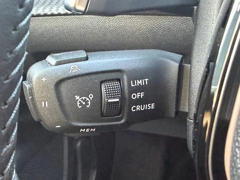 Gros plan sur la commande de régulateur de vitesse au volant d'une Peugeot 2008 rouge Elixir 2024.