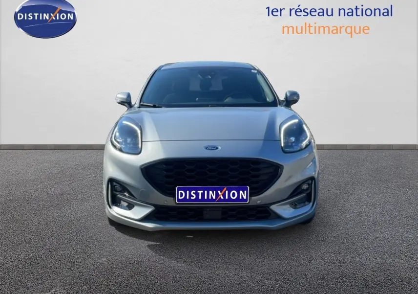 Vue frontale d'un Ford Puma gris Solar Metal 2023 avec calandre noire et phares LED allumés.