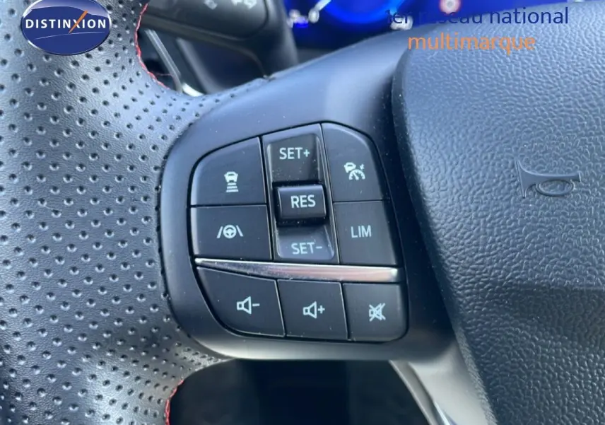 Gros plan sur les commandes de régulateur de vitesse au volant perforé noir du Ford Puma gris Solar Metal 2023.