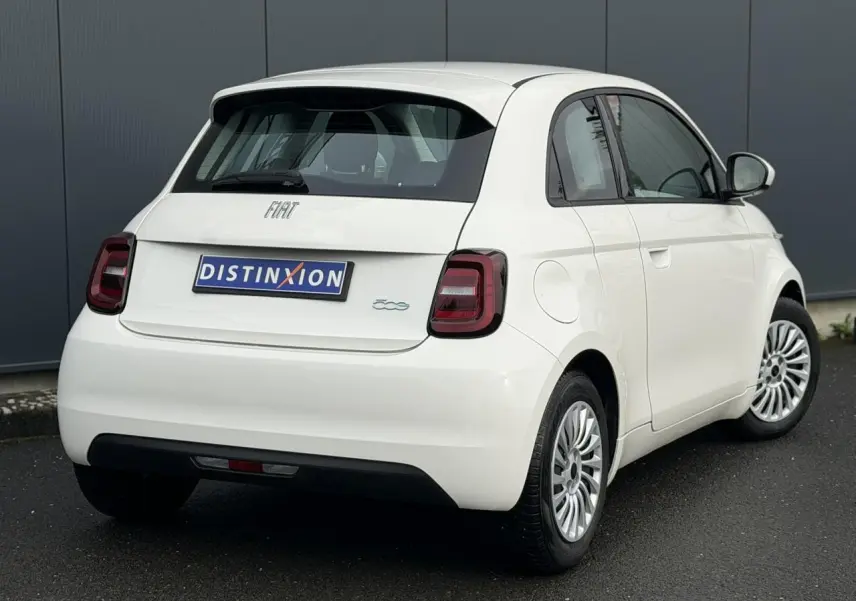 Vue 3/4 arrière droite d'une Fiat 500 électrique blanche avec feux arrière sombres et jantes multibranches.