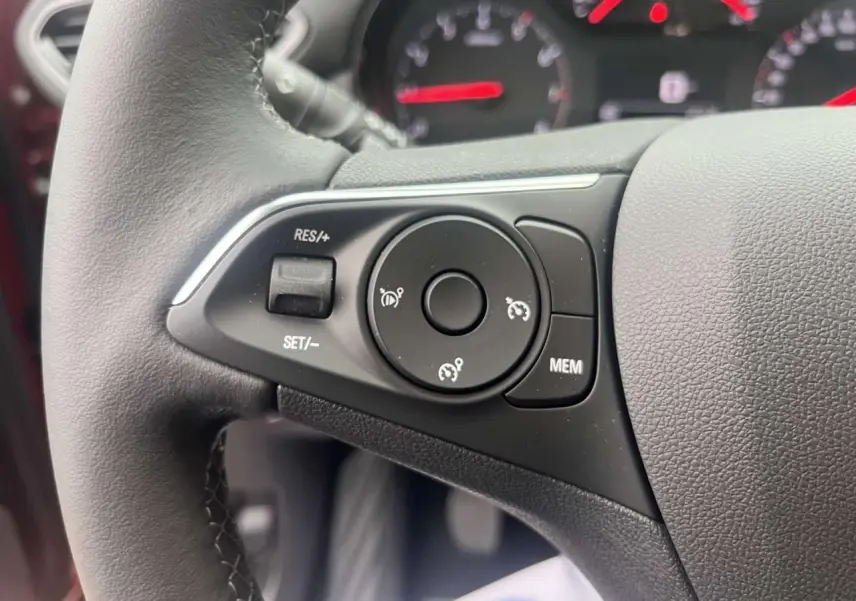 Gros plan sur les commandes au volant à gauche de l'Opel Crossland rouge 2022, avec boutons de régulateur de vitesse.