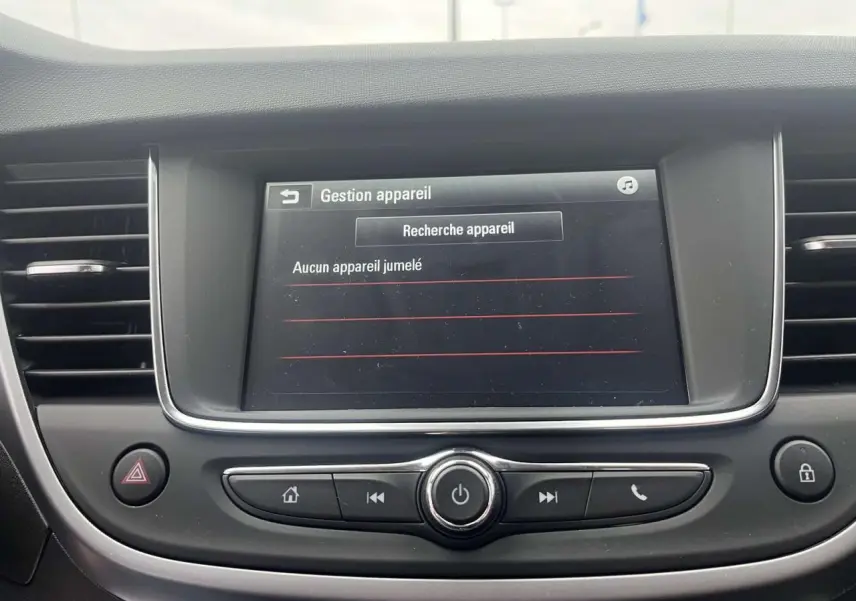 Écran tactile central de l’Opel Crossland rouge 2022 affichant la gestion des appareils Bluetooth, boutons de commande en dessous.