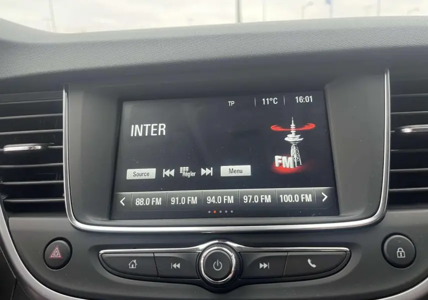 Écran tactile multimédia de l’Opel Crossland rouge 2022 affichant les stations FM avec commandes intégrées au tableau de bord.