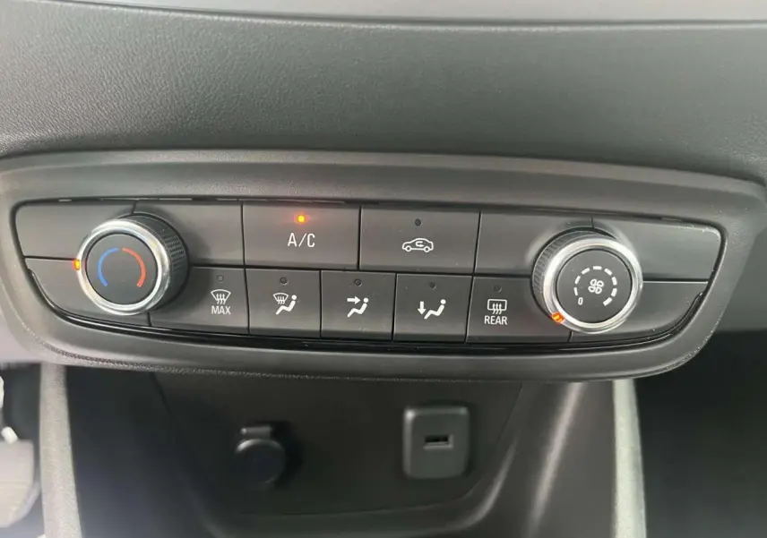 Vue rapprochée de la console de climatisation manuelle de l'Opel Crossland rouge, avec boutons et voyants allumés.