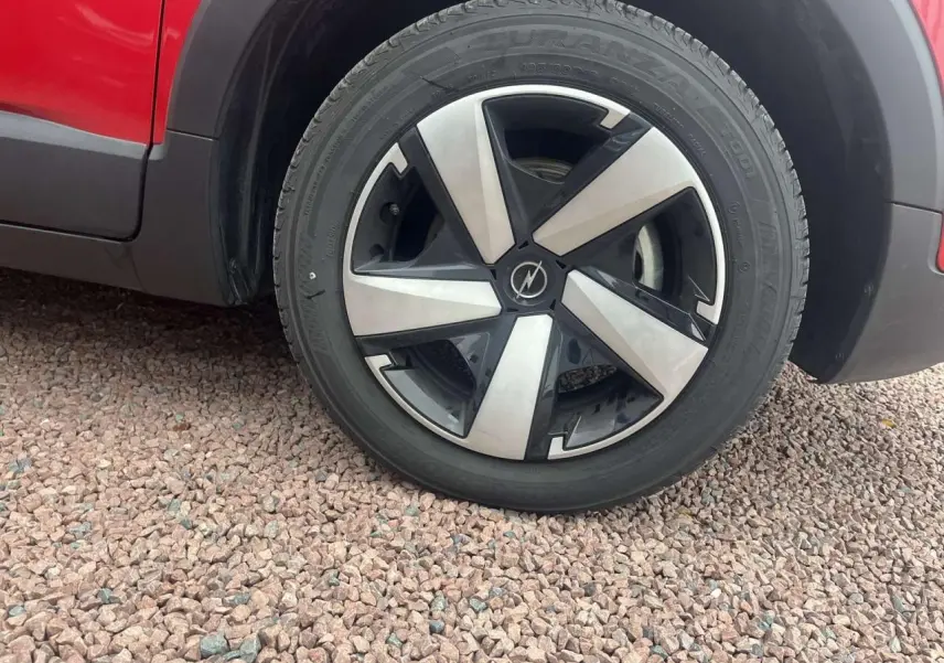 Gros plan sur la roue avant gauche d'un Opel Crossland rouge 2022, soulignant la jante noire et argentée au design moderne.