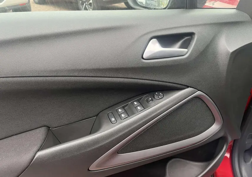 Intérieur côté gauche de la porte avant rouge d'une Opel Crossland 2022, avec commandes de vitres et poignée argentée.