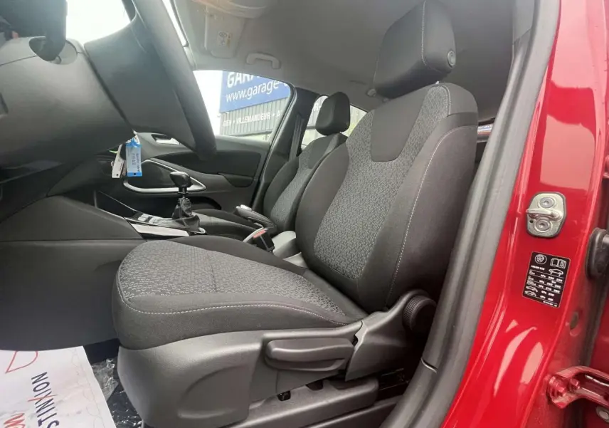 Vue intérieure côté conducteur de l'Opel Crossland rouge 2022, montrant les sièges et la boîte manuelle.