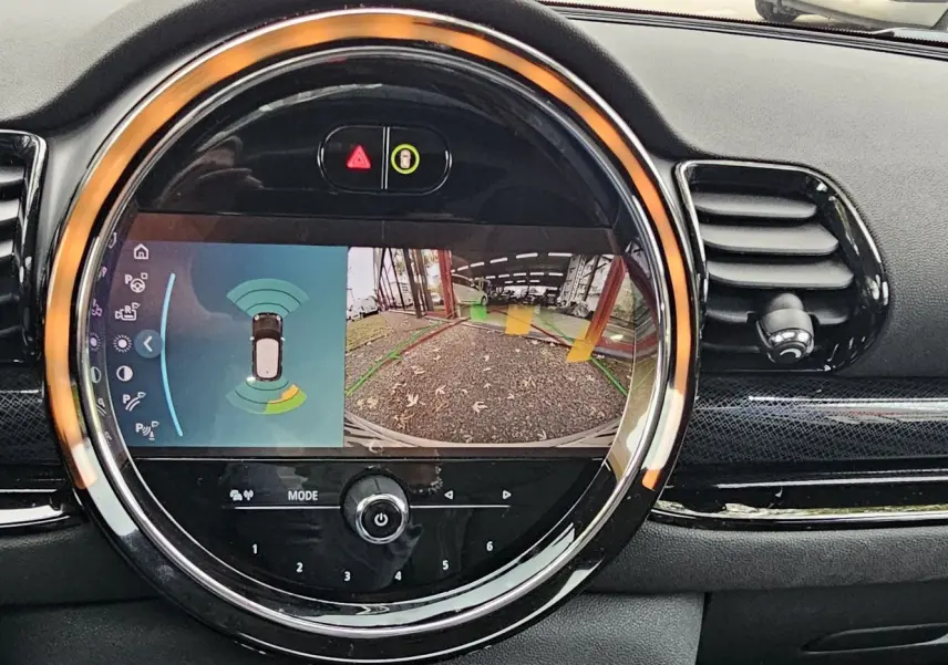 Écran central rond affichant la caméra de recul et les capteurs de stationnement dans une MINI Clubman grise de 2022.