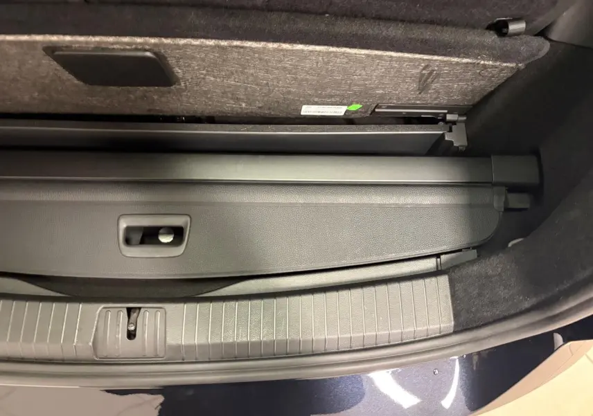 Gros plan sur le coffre ouvert du Volkswagen Touran noir intense nacré, montrant la plage arrière rétractable.